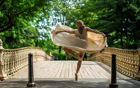Девушка балерина в стойке на мосту