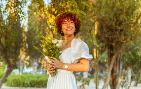 Красивая улыбающаяся рыжеволосая девушка с букетом