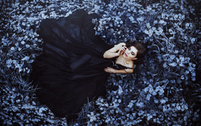 Девушка в черном платье лежит в траве