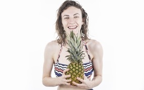 Улыбающаяся девушка с ананасом в руках