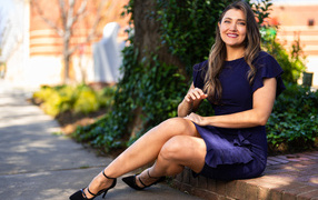 Улыбающаяся женщина в синем платье сидит на земле