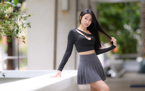 Молодая азиатка в короткой серой юбке