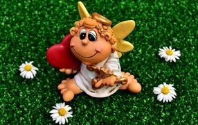 Статуэтка ангела на зеленой траве с белыми ромашками