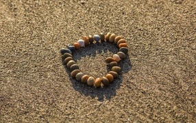 Сердце из камней на морском песке летом