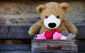 Игрушечный медвежонок с сердечками в деревянном ящике