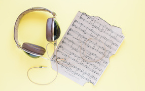 Старые ноты и наушники на желтом фоне