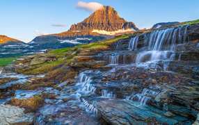Водопад стекает по камням у высокой горы