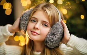 Красивая голубоглазая девочка в меховых наушниках