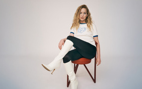 Актриса Дженнифер Лоуренс сидит на стуле на сером фоне