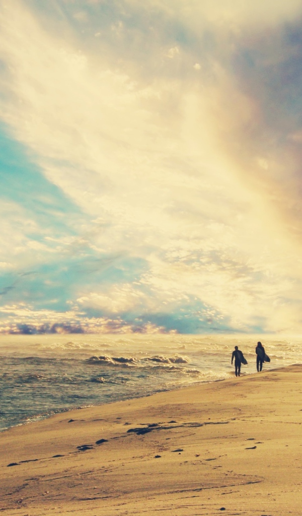 Двое идут по солнечному пляжу