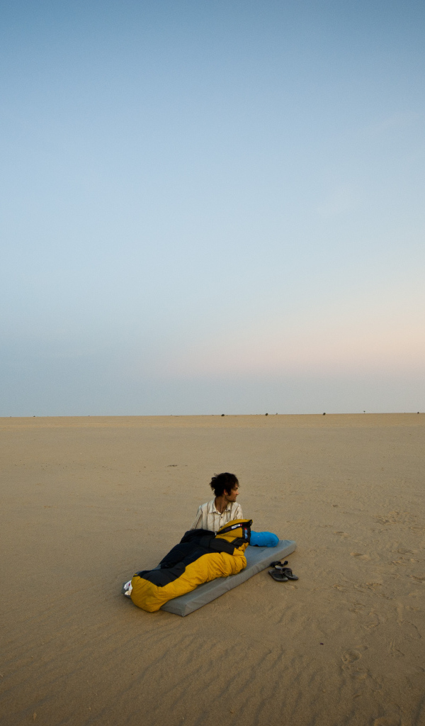 Мужчина на матрасе на пляже