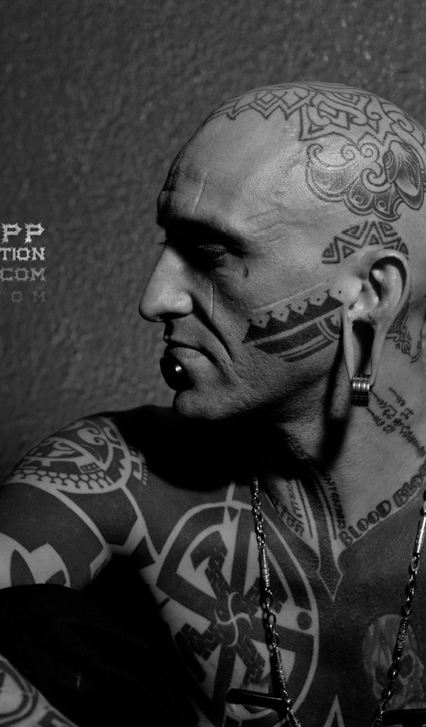 Мужчина с пирсингом в губе и татуировками