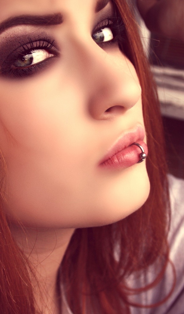 Молодая девушка шатенка с пирсингом в губе