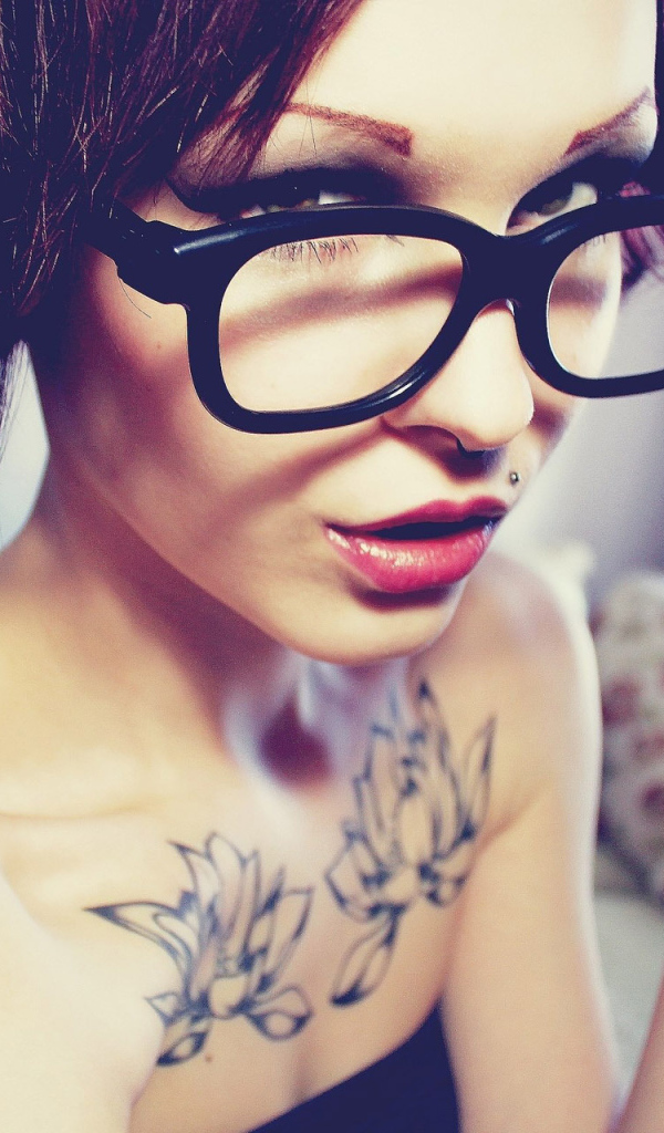 Young brunette woman with short hair wearing glasses and a lip piercing