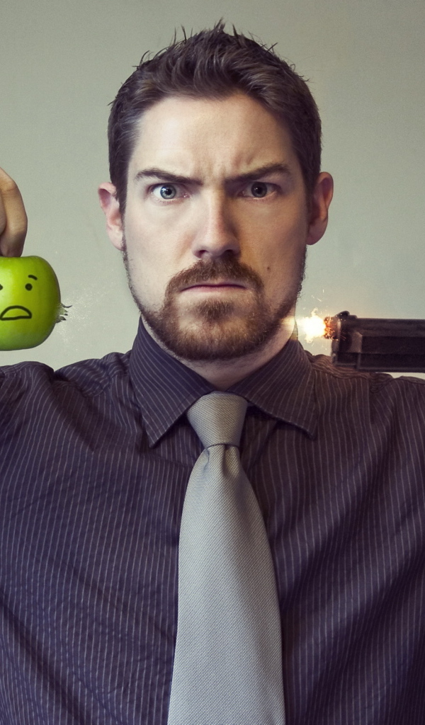 Мужчина стреляет в яблоко