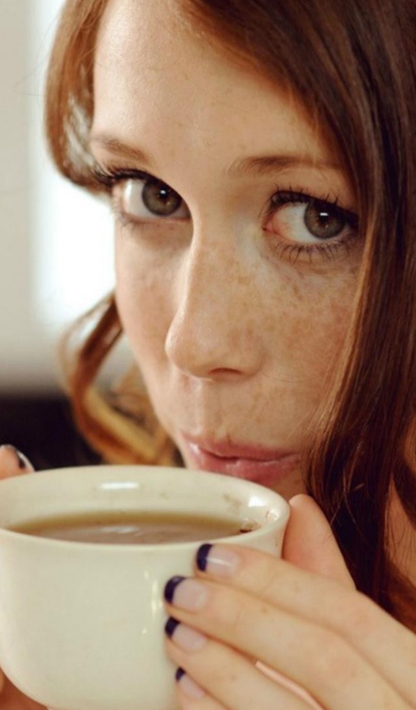 Девушка с веснушками пьет кофе