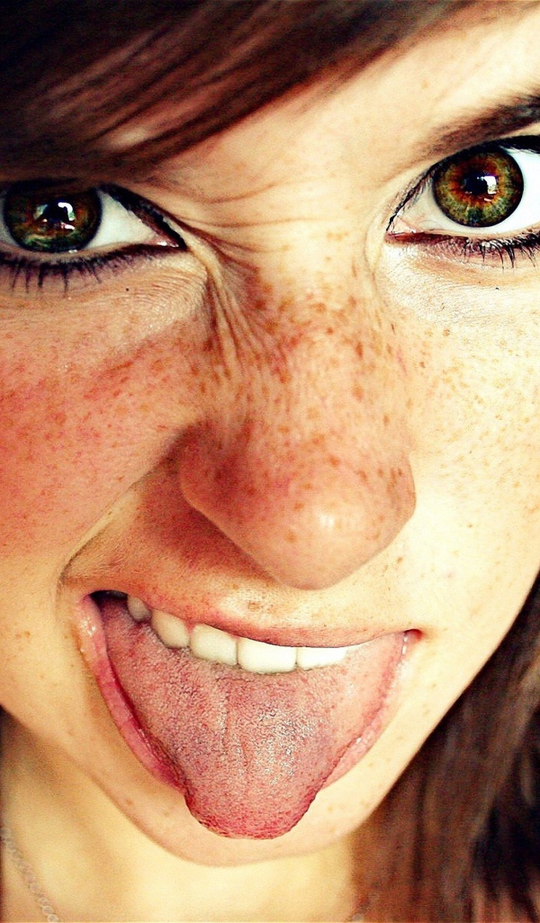 Девушка с веснушками показывает язык