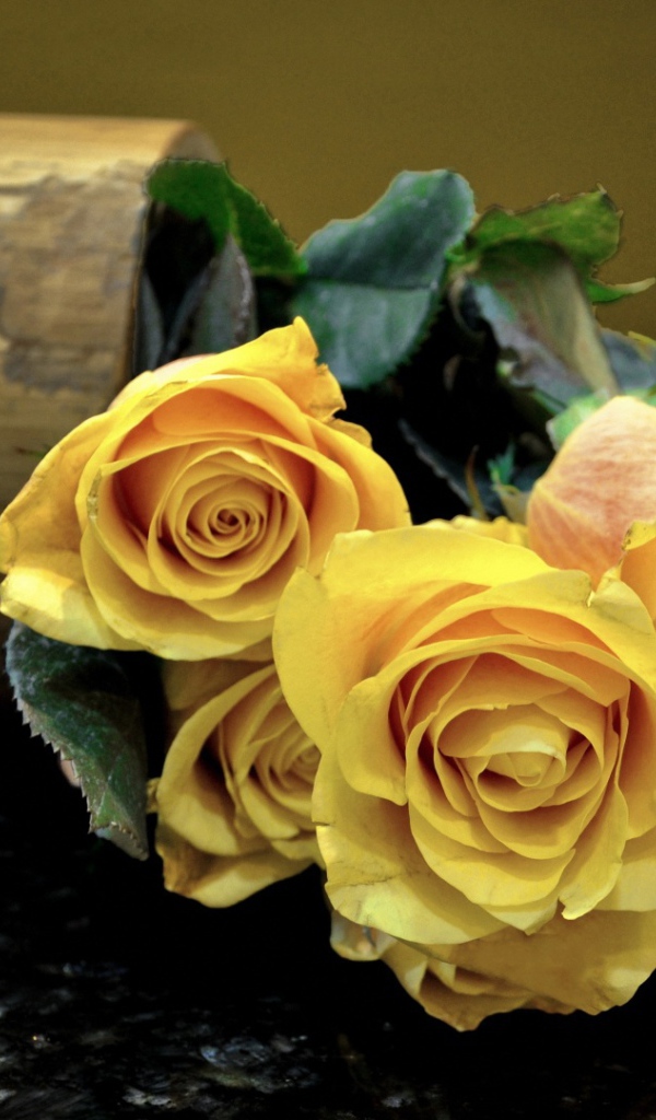 Жёлтые розы на тёмном столе
