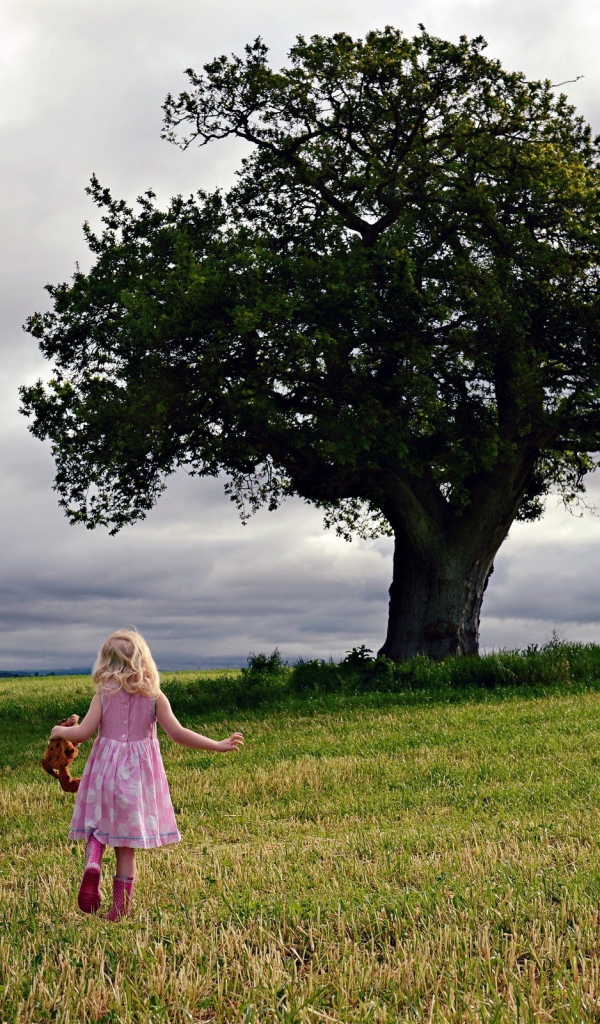 Маленькая девочка бежит к дереву