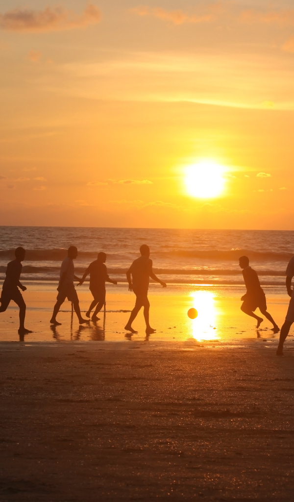 Парни играют в футбол на пляже в Гоа