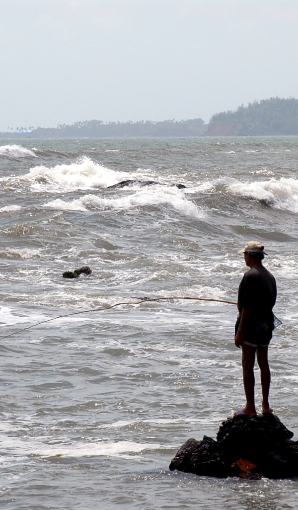 Мужчина ловит рыбу в Гоа