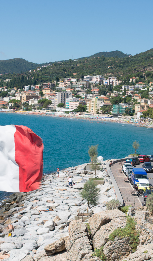 Флаг на фоне пляжа на курорте Алассио, Италия