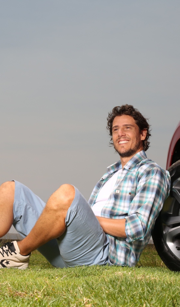 Мужчина сидит у колеса своего автомобиля