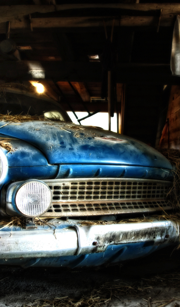 Старый автомобиль присыпан сеном в сарае
