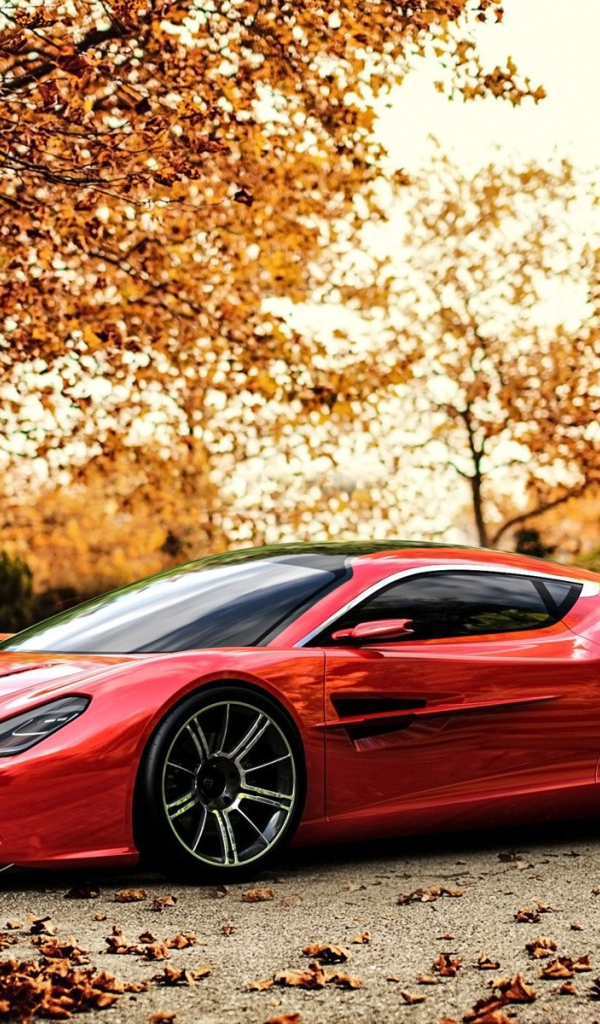 Красный Aston Martin на фоне осенних деревьев