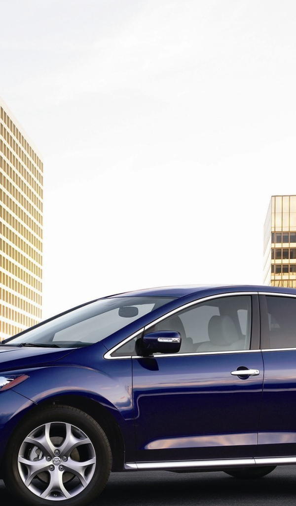 Семейный автомобиль Мазда на фоне городских зданий