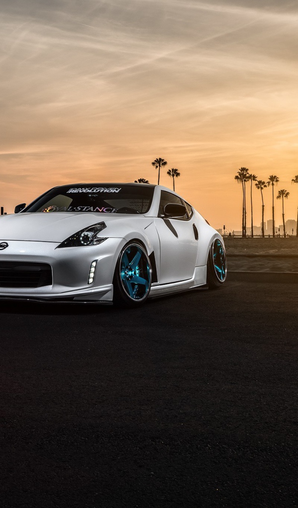 Белый Nissan 370Z на фоне пальм и заката