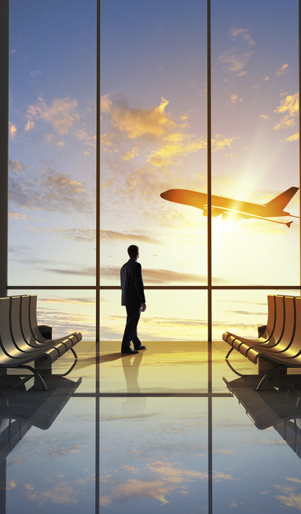 Мужчина смотрит в окно на взлетающий самолет