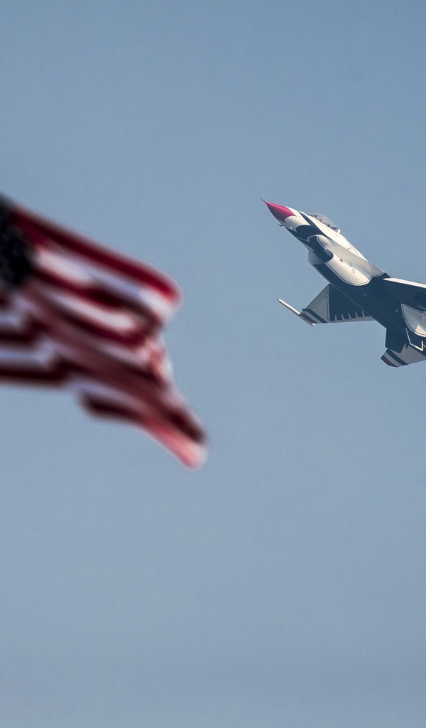 Истребитель F-16 Fighting Falcon пролетает над флагом США