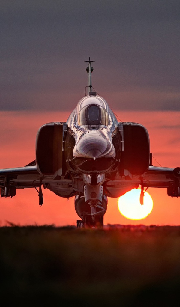 Истребитель F-4 Phantom II стоит на фоне заката