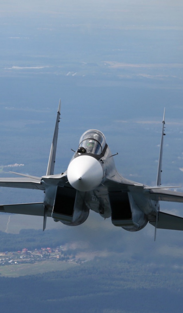 Самолет СУ-27 летит над городом