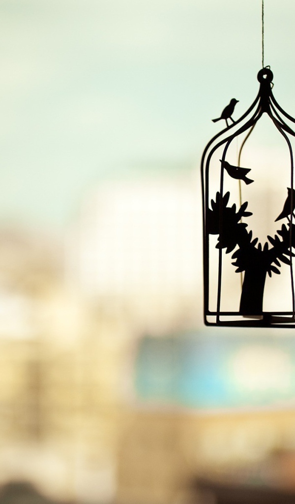 Силуэт клетки для птиц на нечетком фоне