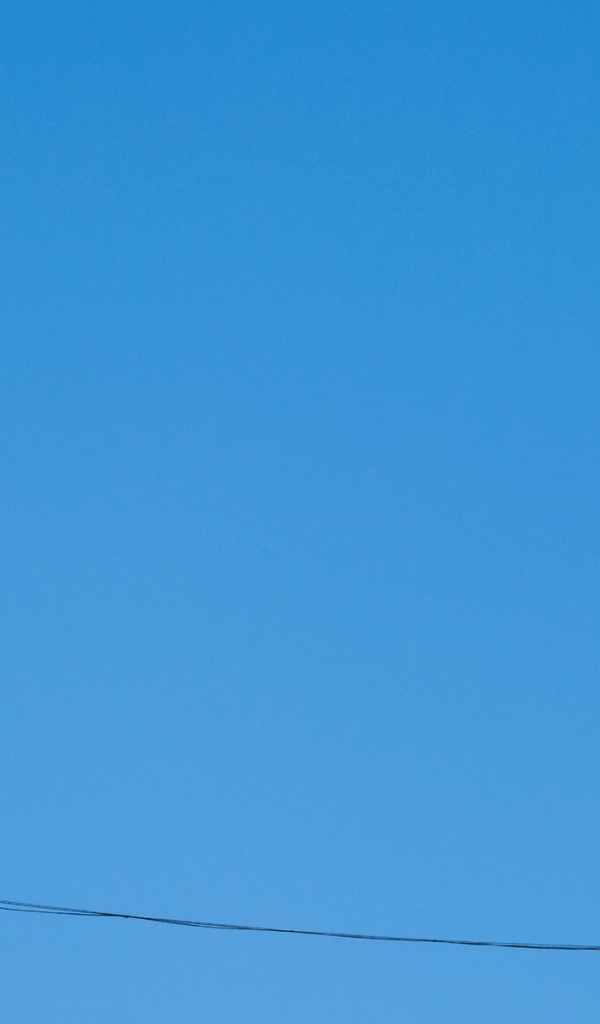 Кеды висят на проводе на фоне голубого неба