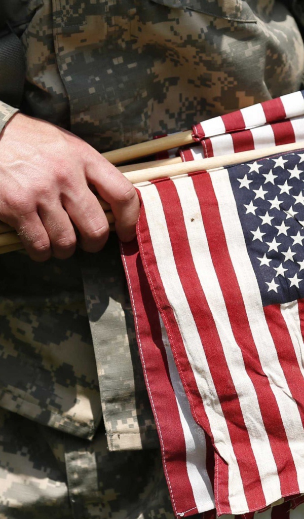 Солдат держит в руке флаги США
