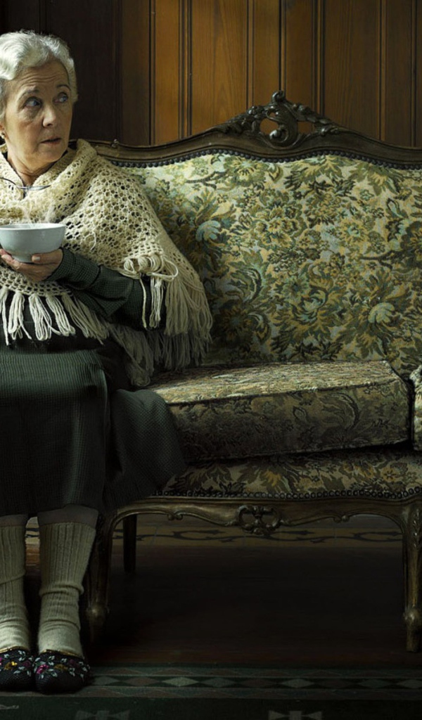 Пожилая женщина кушает суп и смотрит на пингвина