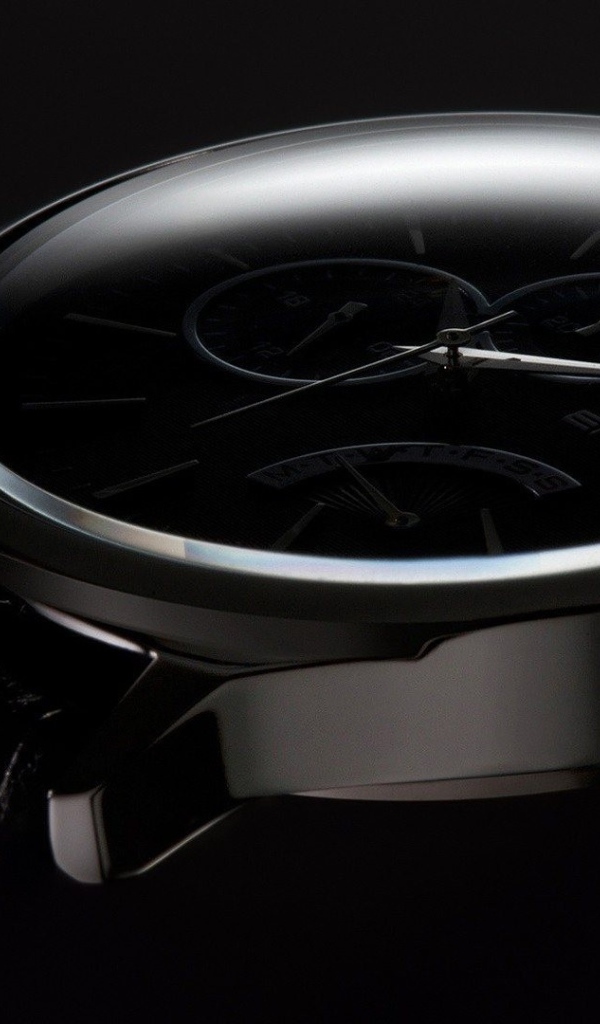 Дорогие черные часы на черном фоне