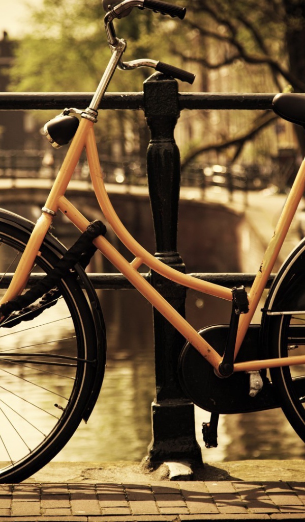 Оранжевый велосипед прислонен к перилам