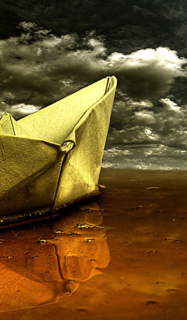 Бумажный кораблик на песке пляжа