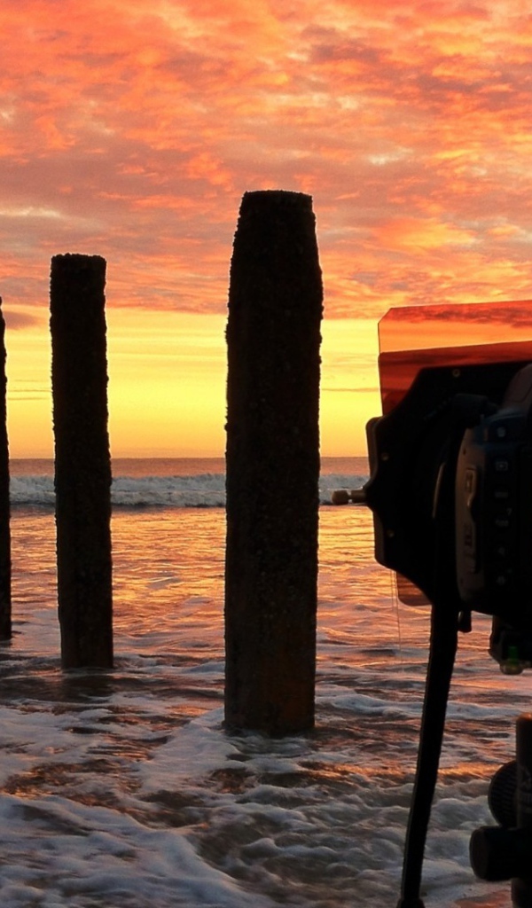 Фотограф снимает закат на берегу моря