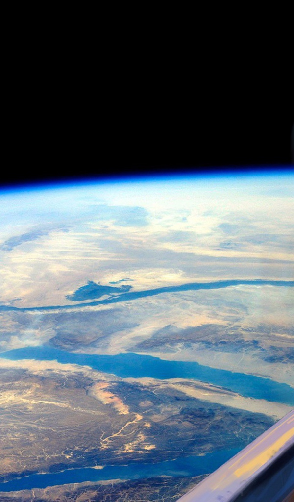 Девушка блондинка смотрит в окно на Землю