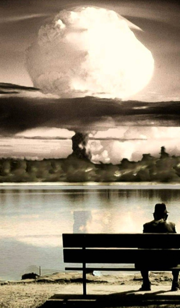 Человек смотрит на ядерный взрыв сидя на скамье