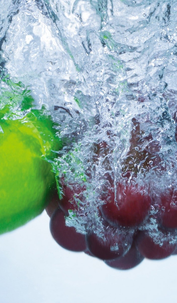 Зеленый лимон и кисть винограда в воде