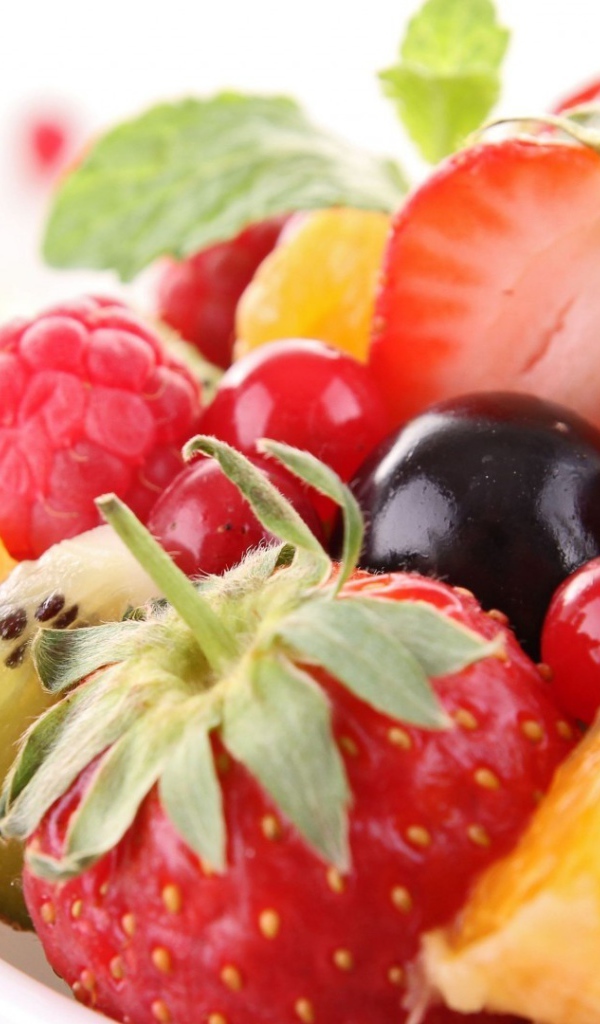 Кусочки спелых фруктов и ягоды на тарелке