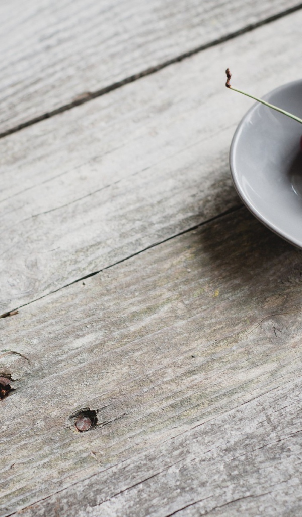 Две красных вишни в керамической чашке