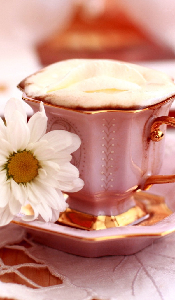 Кофе с пенкой и ромашка на блюдце