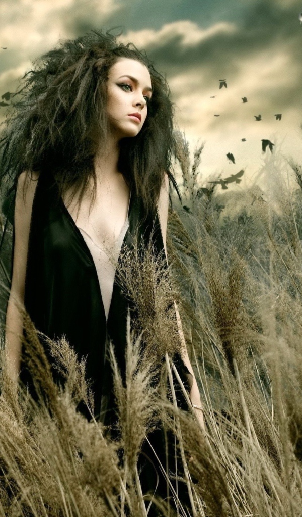 Девушка в поле во время сильного ветра